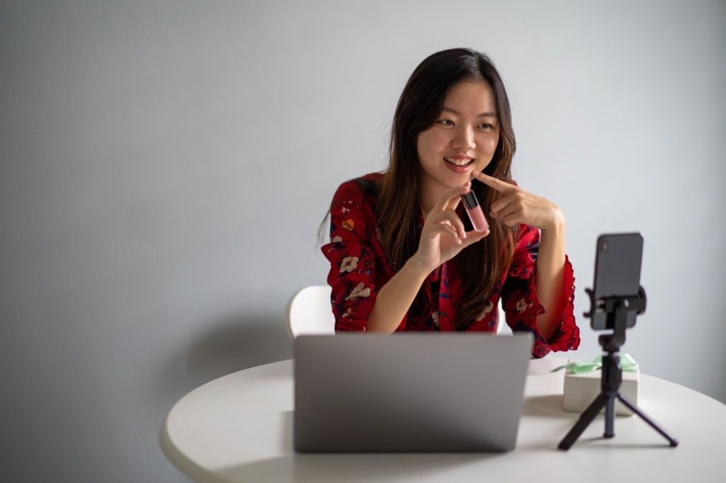 Young asian woman using live social media to sell her product via smartphone